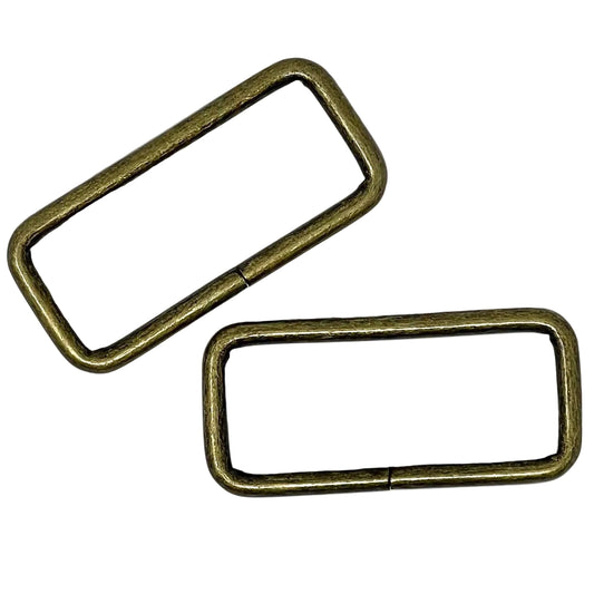Two brass-colored rectangular rings on a white background